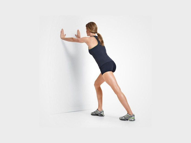 Kéo giãn cơ dép với động tác đứng đối tường